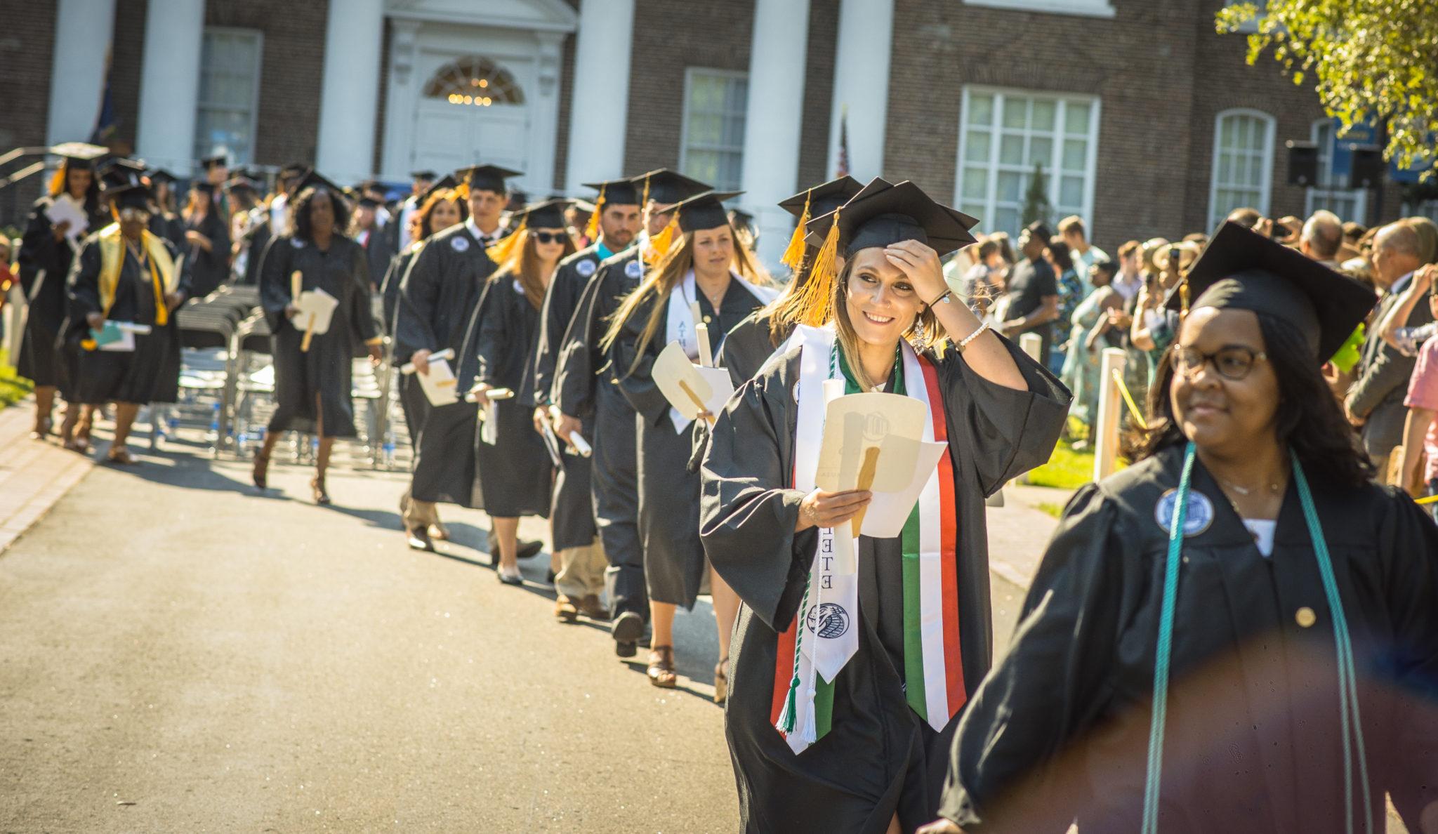 A row of students walking away in a line from their seats at their graduation during the recessional.